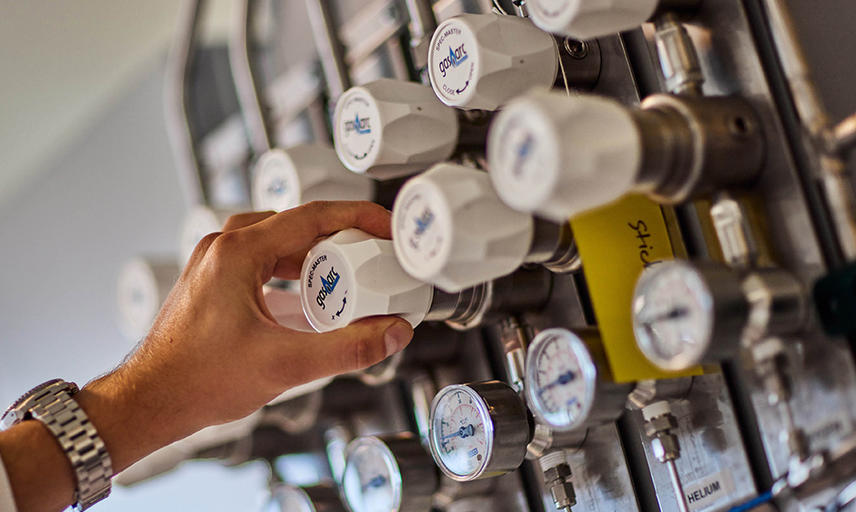 photo of researcher hand in catalysis hub labs at gas pipes